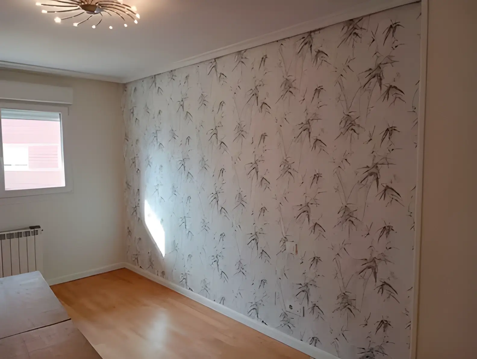 Los Pintores Tarragona colocando papel pintado en pared de acento de habitación luminosa