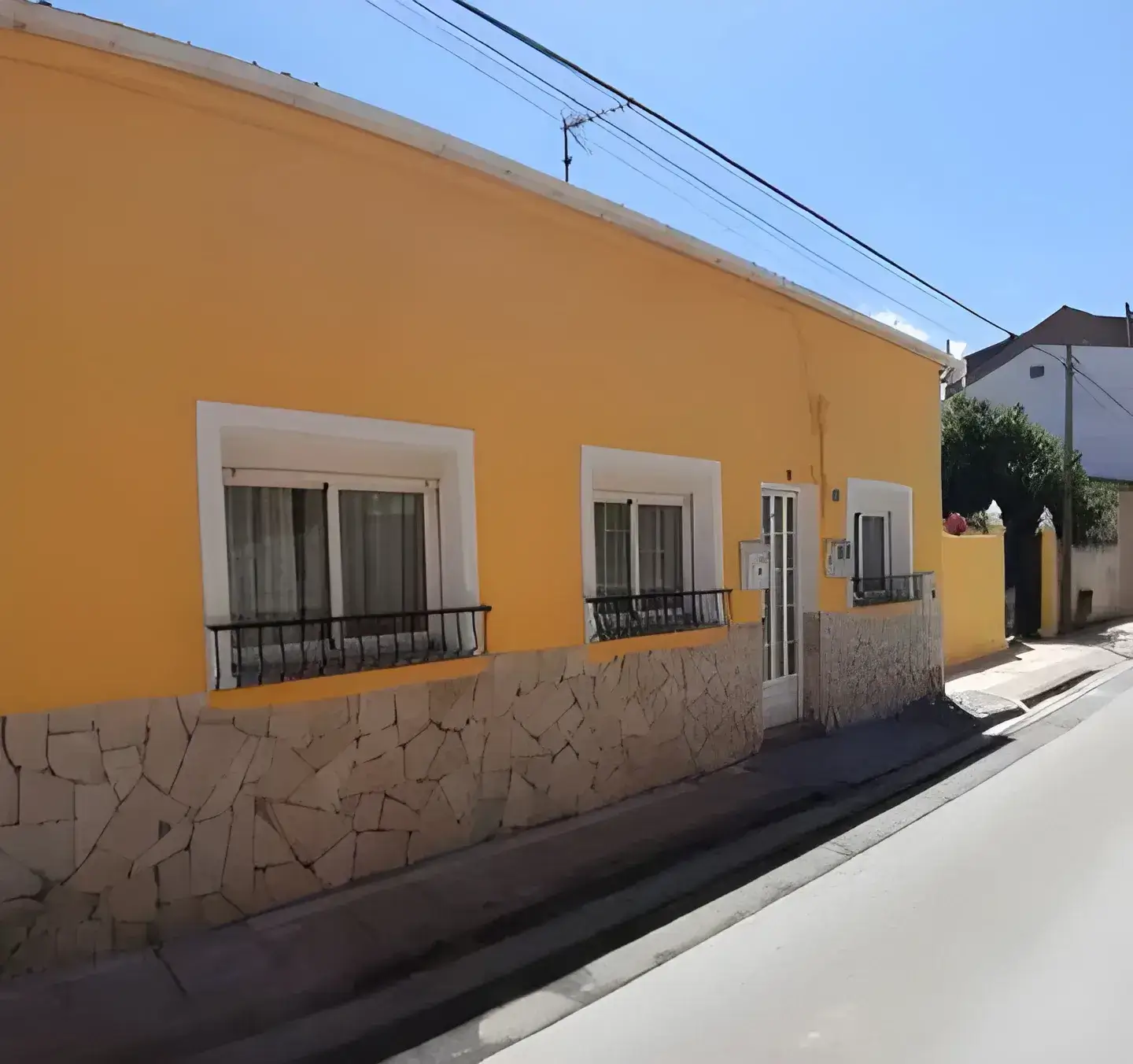 Los Pintores Zaragoza Fachada de casa tradicional pintada en color amarillo con zócalo de piedra